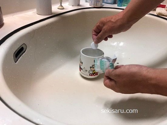 入れ歯洗浄剤を水を溜めたコップの中に落とす