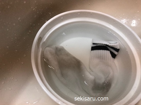 熱いお湯が入った洗面器の中に靴下を入れる