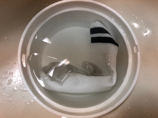 熱いお湯が入った洗面器の中に靴下を浸けこむ